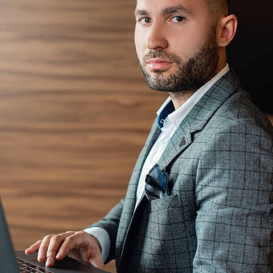 Focused businessman using laptop in a stylish office setting. Emphasizing productivity and style.