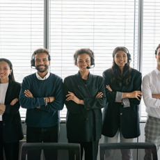 Diverse group of smiling customer service agents wearing headsets in modern office.