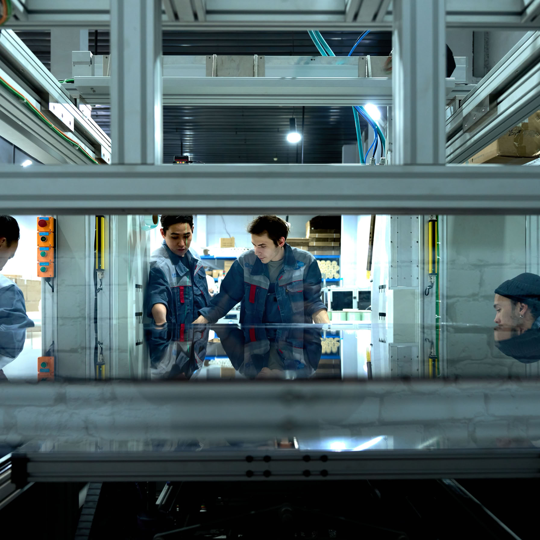 Engineers collaborate over advanced machinery in a high-tech indoor workspace.